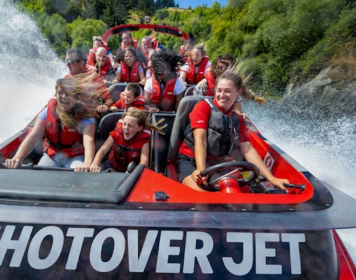 Tourists enjoying a thrilling ride on the Shotover Jet through white water rapids.
