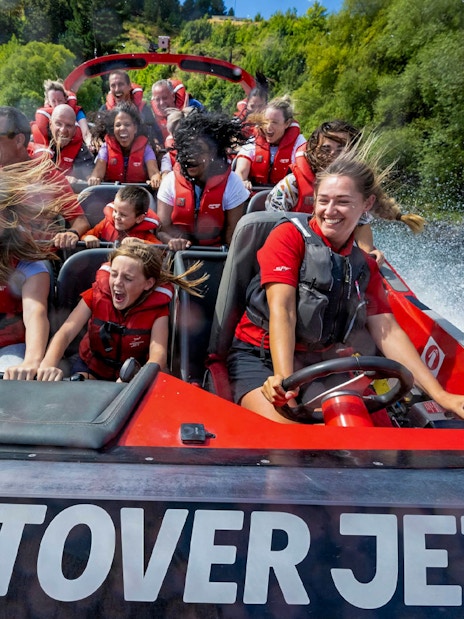 Tourists enjoying a thrilling ride on the Shotover Jet through white water rapids.