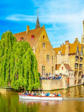 Canal cruise boat passing historic buildings in old town Brugge.