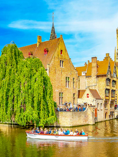 Canal cruise boat passing historic buildings in old town Brugge.