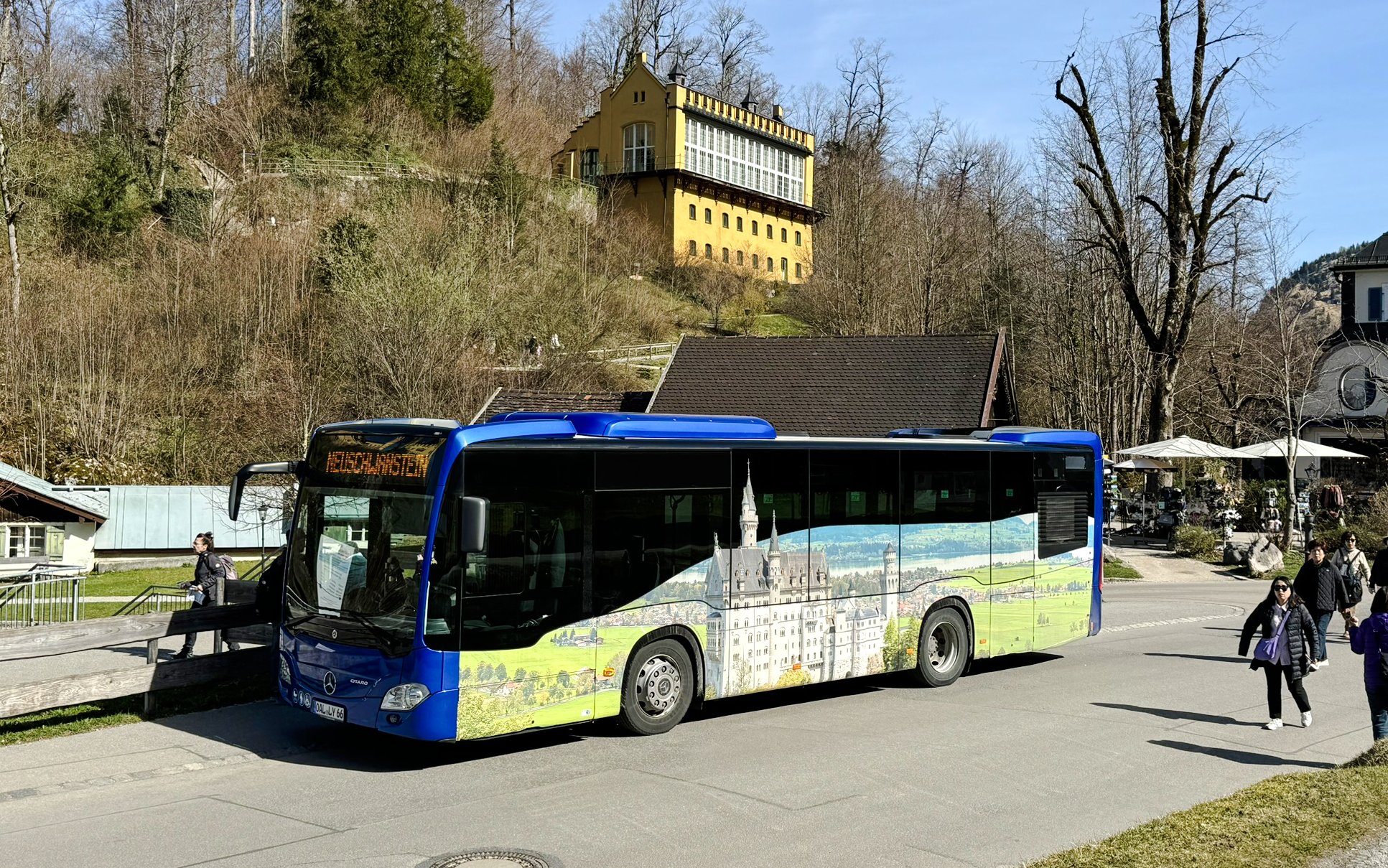 Bus near Hohenschwangau Castle with scenic mural, Germany.