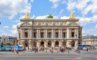 Opera Garnier in Paris with people walking and traffic in front.