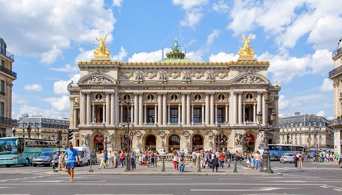 Opera Garnier in Paris with people walking and traffic in front.