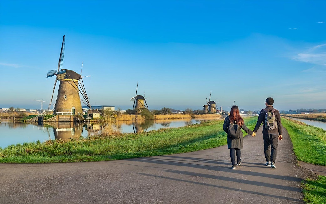 Couple walking towards windmills at Zaanse Schans near Amsterdam.