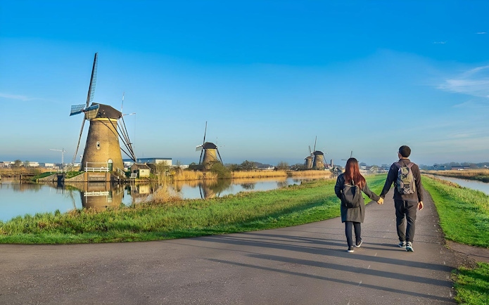 Couple walking towards windmills at Zaanse Schans near Amsterdam.