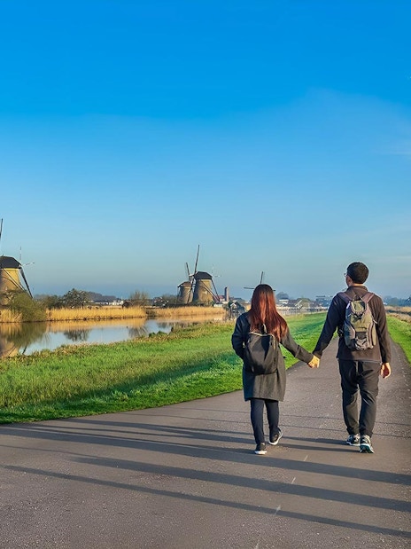 Couple walking towards windmills at Zaanse Schans near Amsterdam.