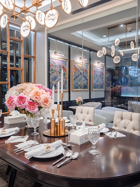 Dining area in The Coral First Class Lounge, Bangkok airport, featuring elegant table setting and floral decor.