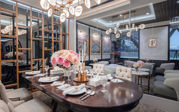Dining area in The Coral First Class Lounge, Bangkok airport, featuring elegant table setting and floral decor.
