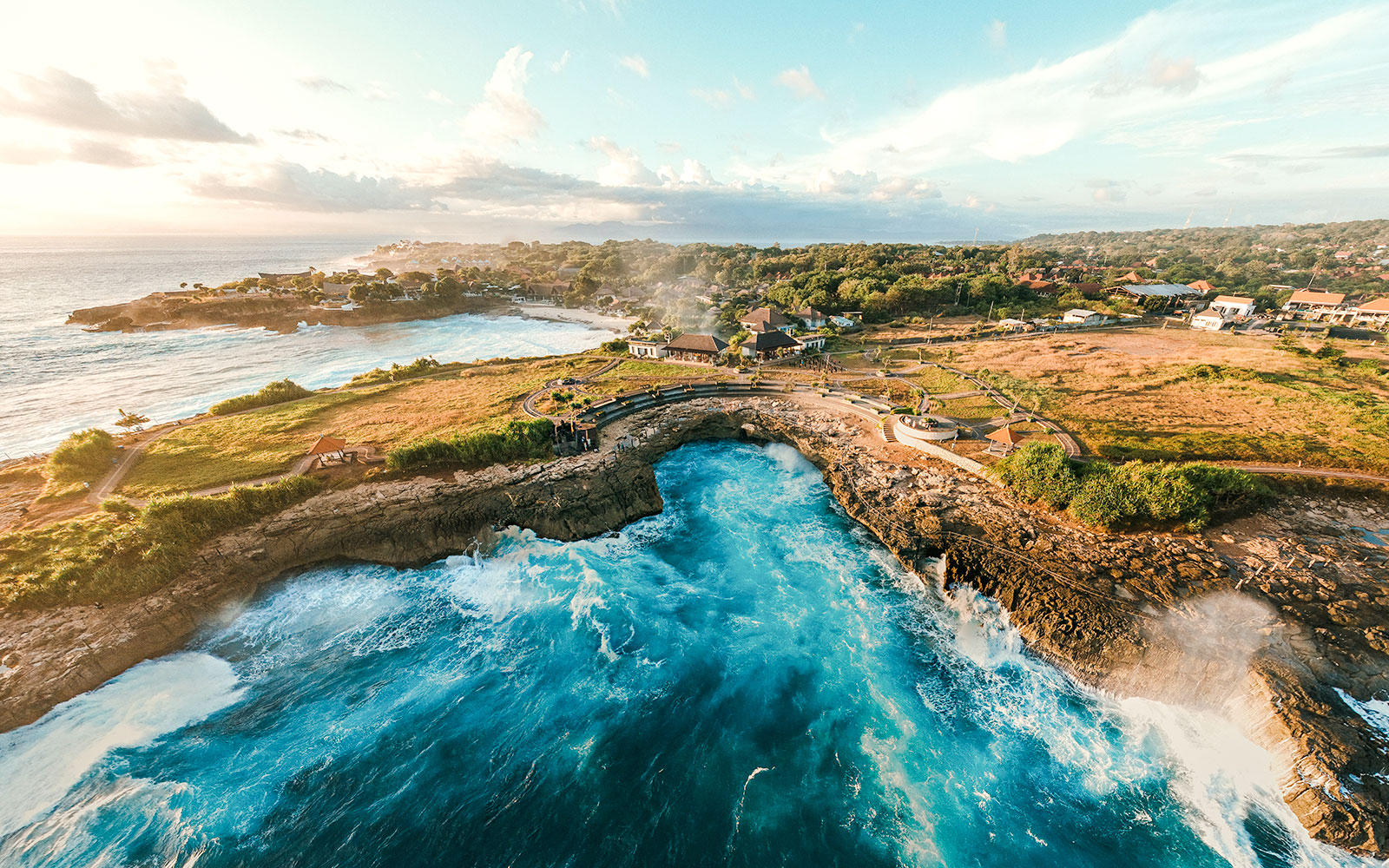 Aerial view of Devil’s Tear in Nusa Lembongan, Indonesia, with waves crashing against rocky cliffs.