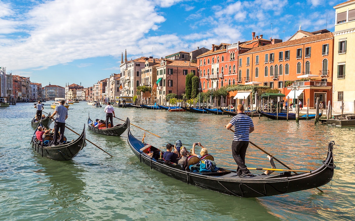 Gondolas navigating Canal Grande in Venice with historic buildings in the background.