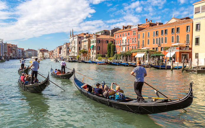 Gondolas navigating Canal Grande in Venice with historic buildings in the background.