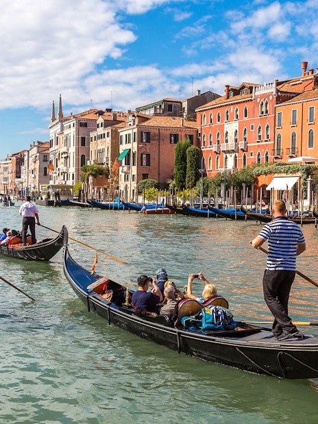Gondolas navigating Canal Grande in Venice with historic buildings in the background.