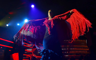 Flamenco dancer performing under stage lights with red shawl, Spain.