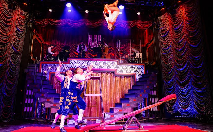 Acrobats performing on stage at Golden Years Show Café, with musicians in the background.