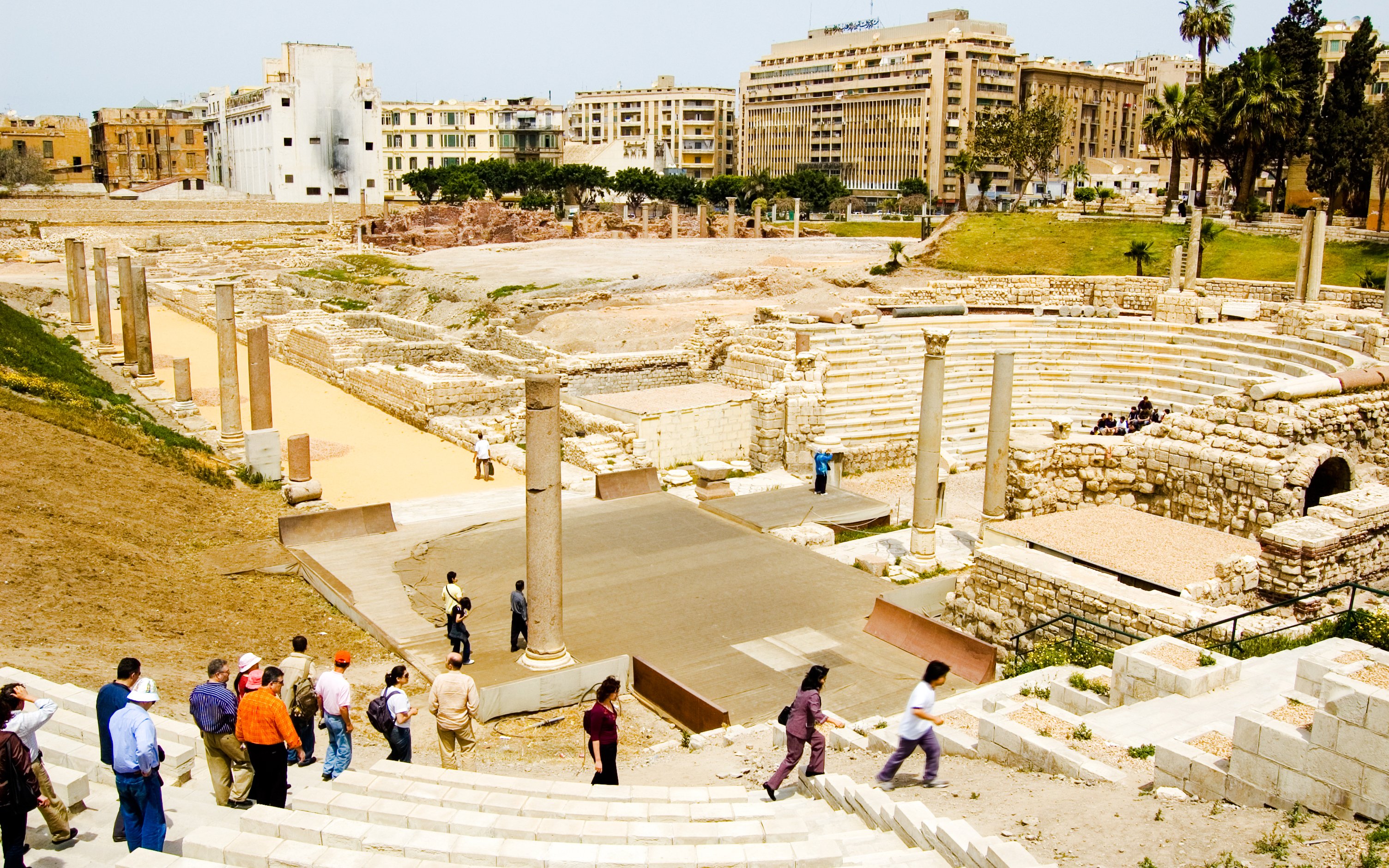 Ancient Roman Theatre in Kom El-Deka, Alexandria, with tourists exploring the ruins.