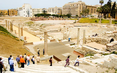 Ancient Roman Theatre in Kom El-Deka, Alexandria, with tourists exploring the ruins.