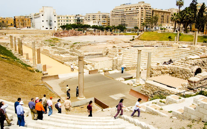 Ancient Roman Theatre in Kom El-Deka, Alexandria, with tourists exploring the ruins.