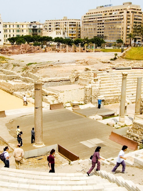 Ancient Roman Theatre in Kom El-Deka, Alexandria, with tourists exploring the ruins.