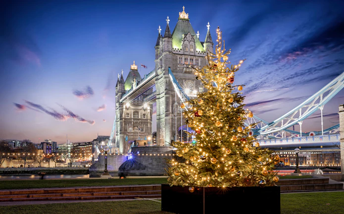 Tower Bridge in London with a decorated Christmas tree in the foreground.