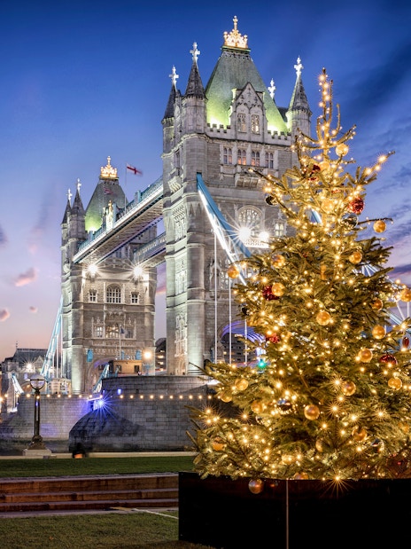 Tower Bridge in London with a decorated Christmas tree in the foreground.