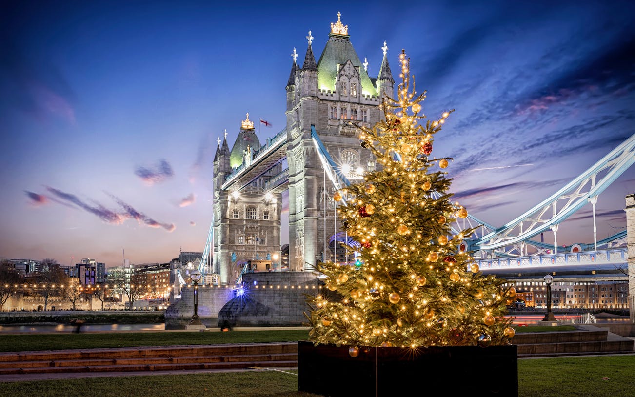 Tower Bridge in London with a decorated Christmas tree in the foreground.