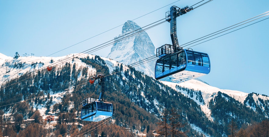 Cable cars ascending to Matterhorn Glacier Paradise with snowy mountain backdrop.