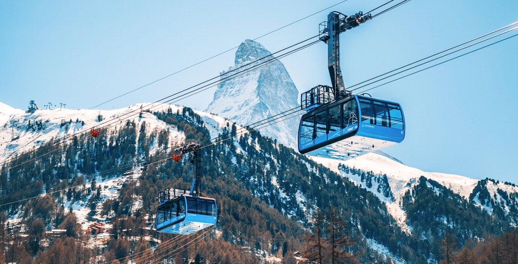 Cable cars ascending to Matterhorn Glacier Paradise with snowy mountain backdrop.