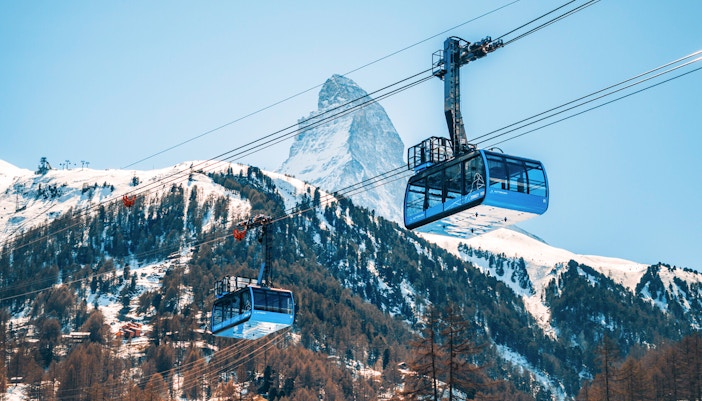 Cable car ascending to Matterhorn Glacier Paradise with snow-covered peaks in Zermatt, Switzerland.