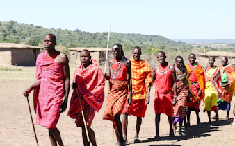 Maasai villagers in traditional attire walking in a village in Zanzibar.