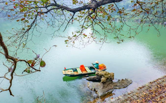Boat on river at Trang An Landscape Complex, Vietnam, with limestone rocks and overhanging branches.