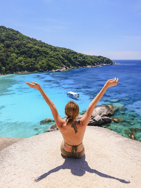 Person sitting on rock overlooking turquoise waters of Island No. 8, Similan Islands.