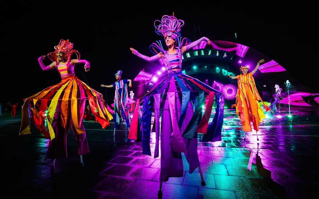 Performers in colorful costumes on stilts at the Kiss of the Sea Show.