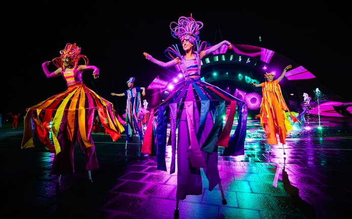 Performers in colorful costumes on stilts at the Kiss of the Sea Show.