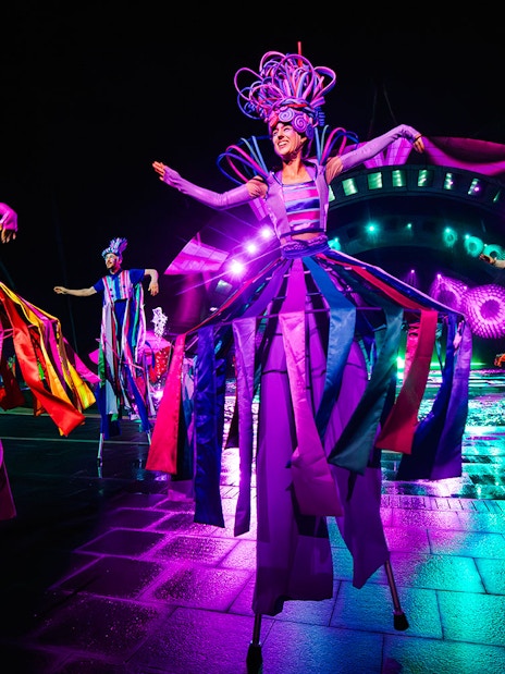 Performers in colorful costumes on stilts at the Kiss of the Sea Show.