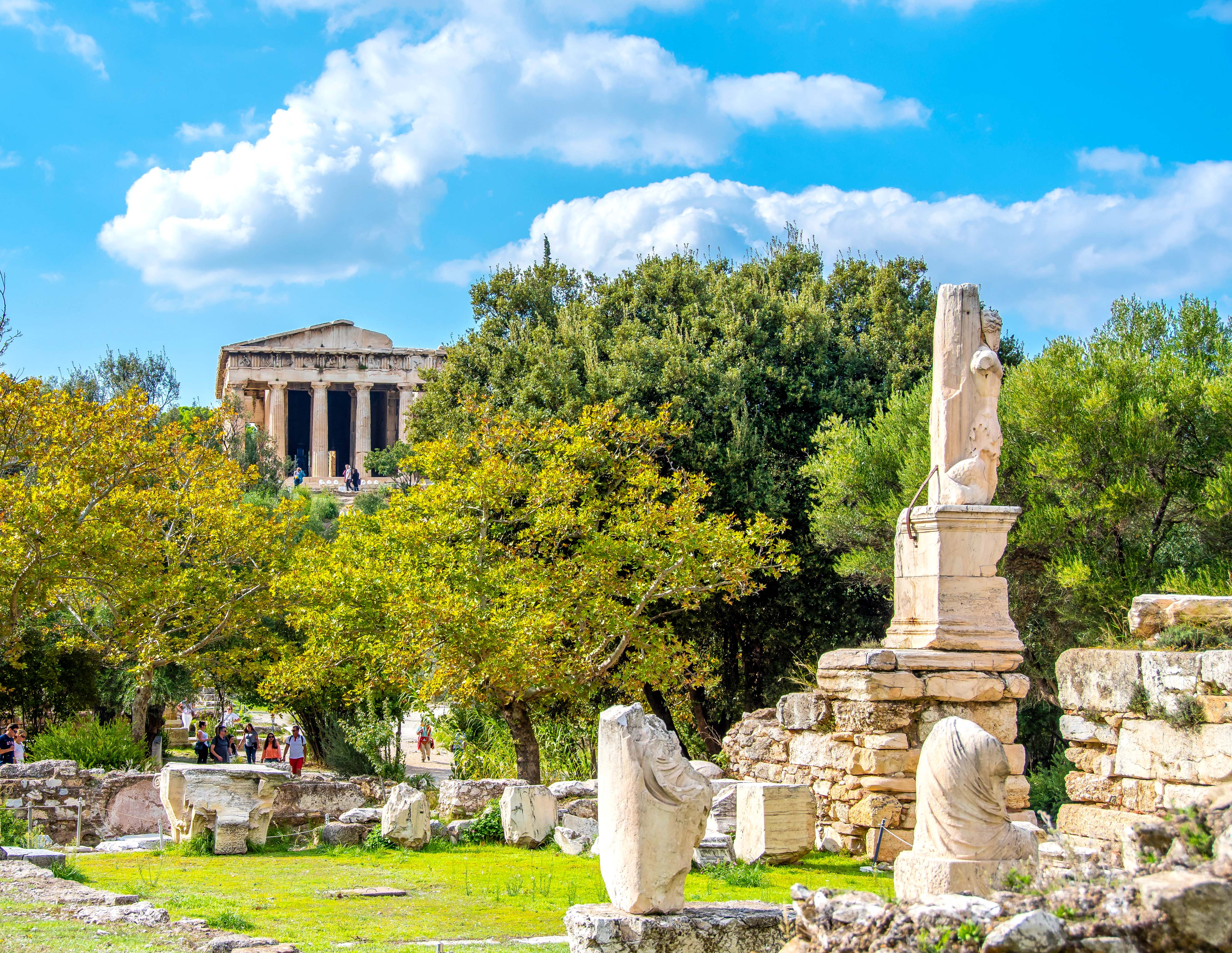 Ancient ruins of the Altar of the Twelve Gods in Athens, Greece, surrounded by trees.