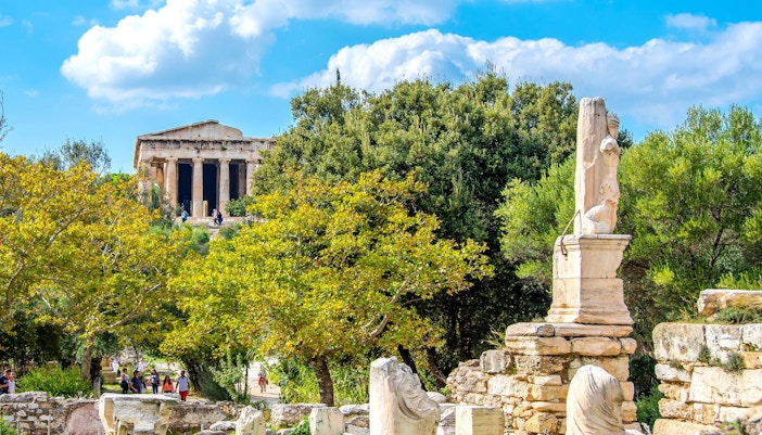Ancient ruins of the Altar of the Twelve Gods in Athens, Greece, surrounded by trees.