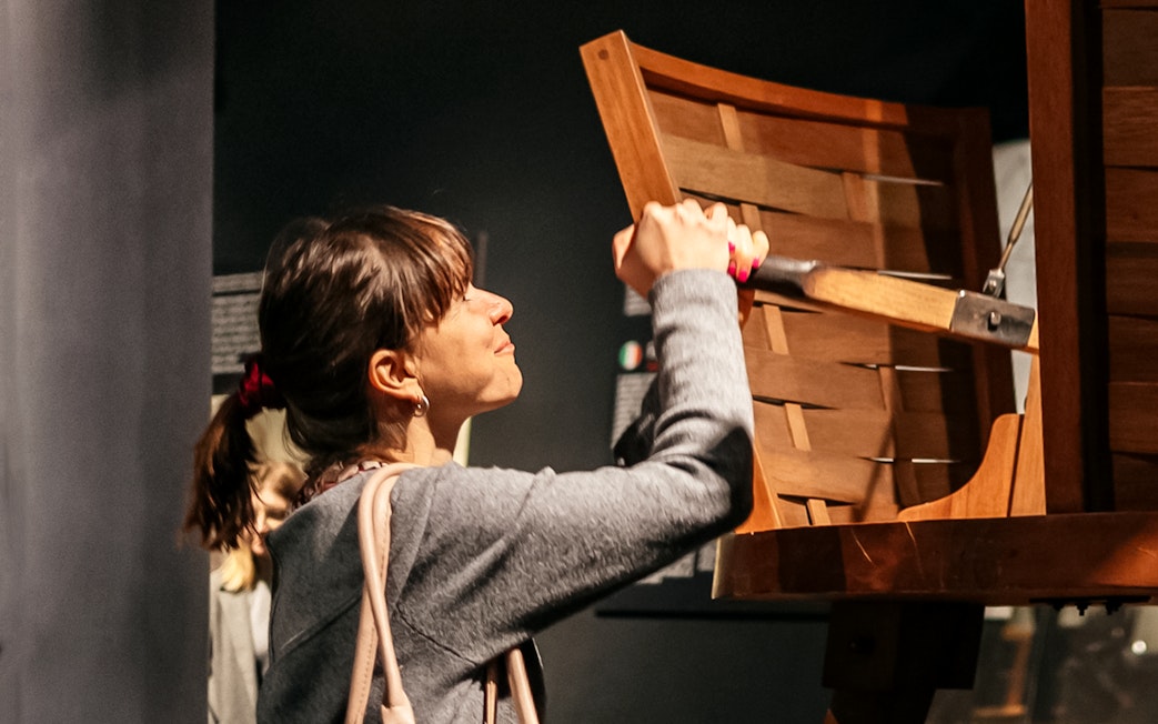 Visitor interacting with a wooden exhibit at Leonardo Interactive Museum.