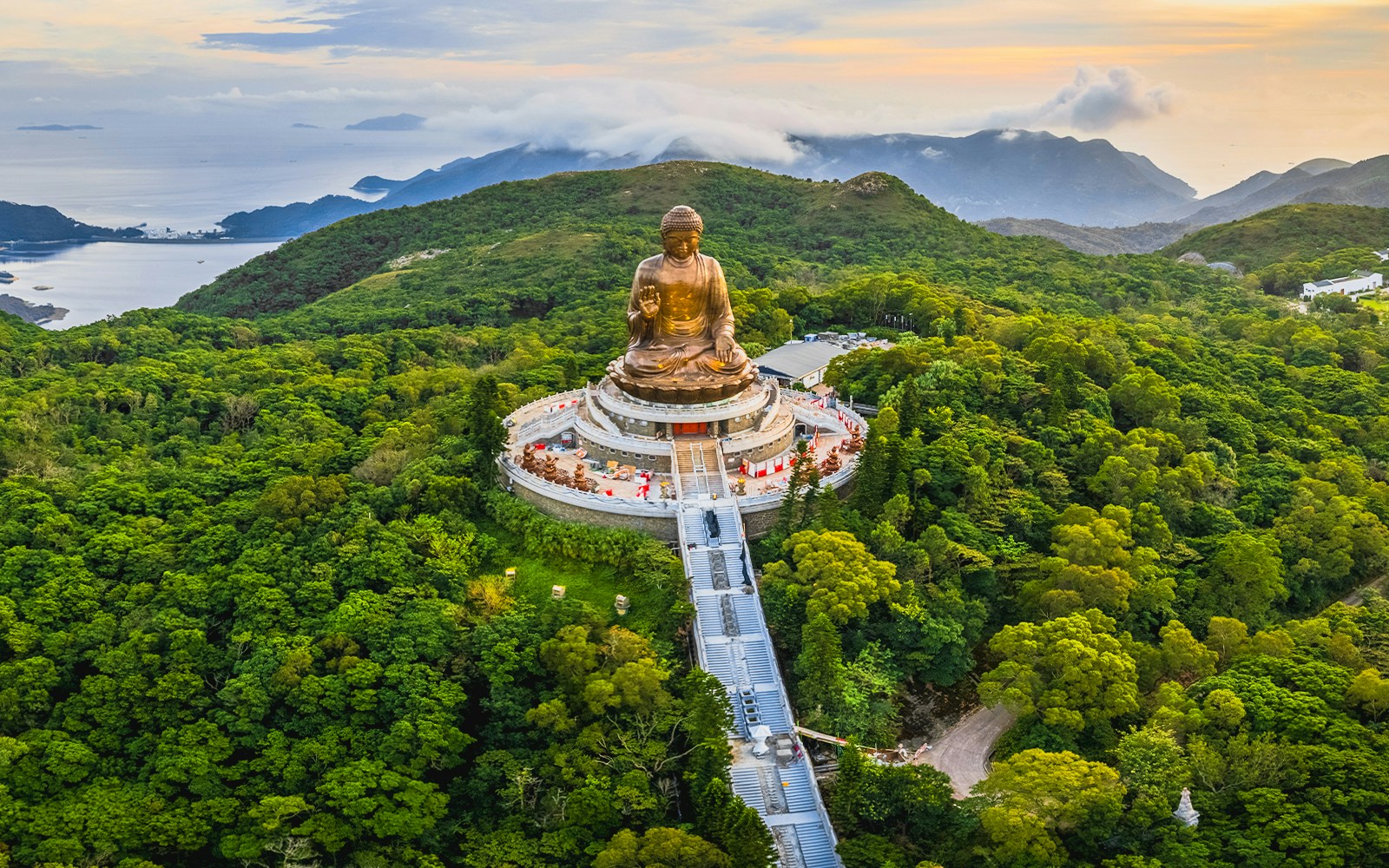 Tian Tan Buddha statue surrounded by lush hills in Hong Kong.