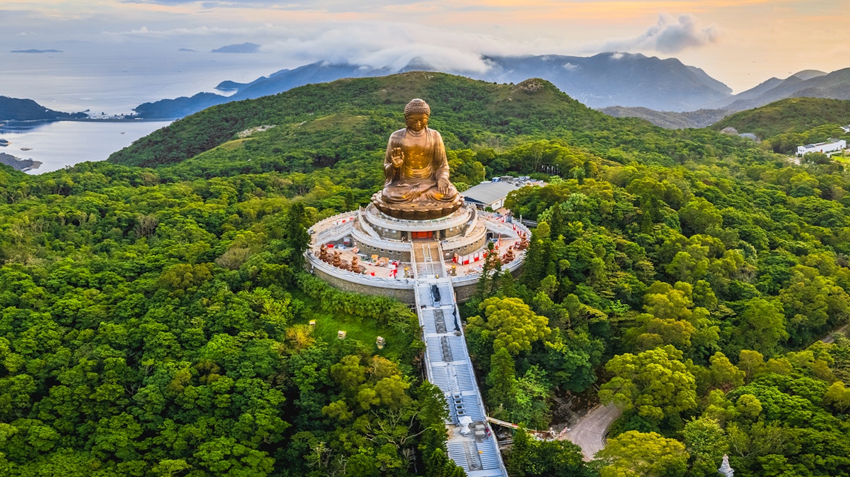 Tian Tan Buddha statue surrounded by lush hills in Hong Kong.