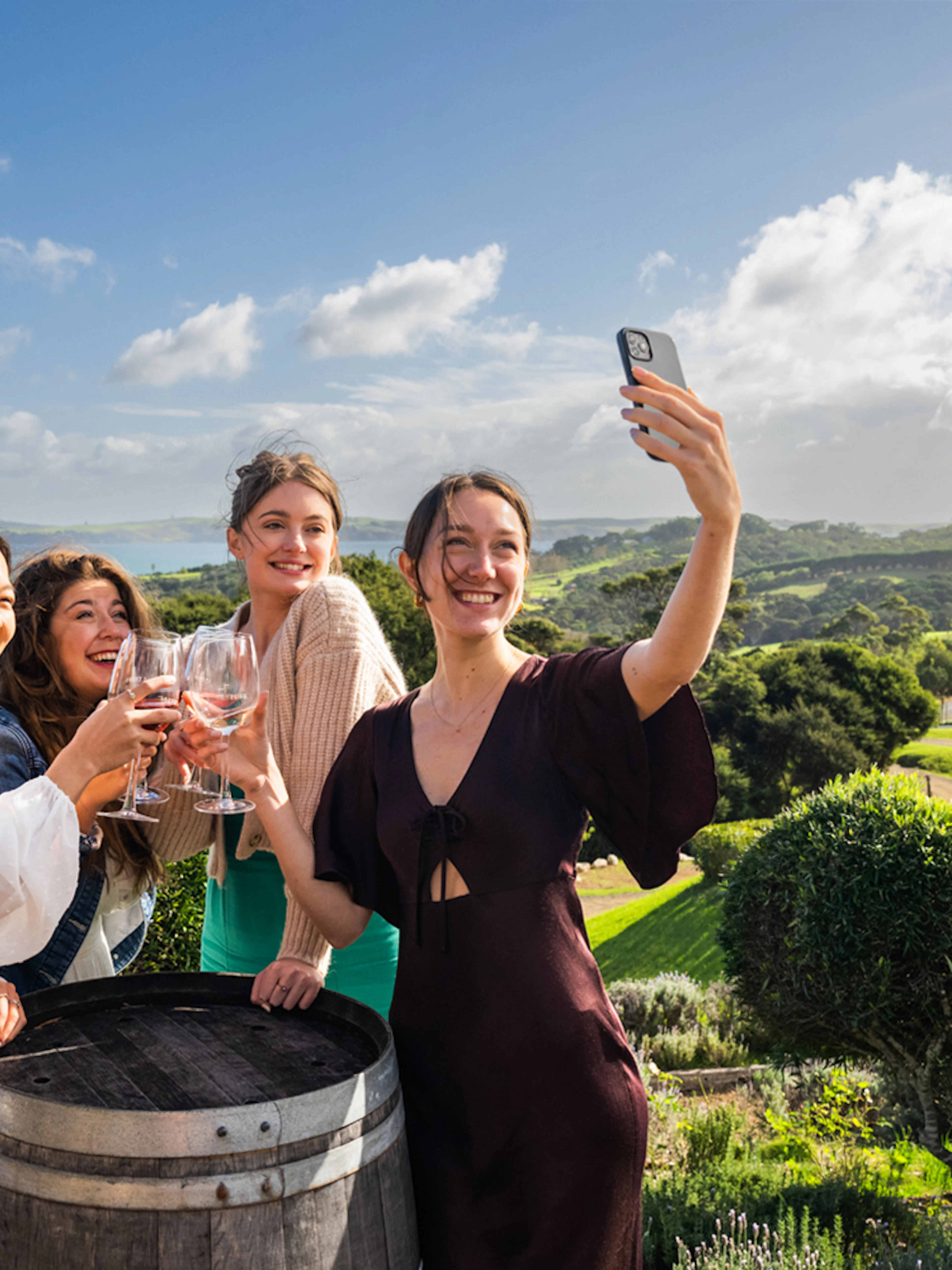 Friends enjoying wine at Stonyridge Winery, Waiheke Island, with scenic vineyard views.