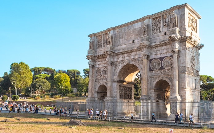 Arch of Constantine in Rome with tourists exploring nearby.