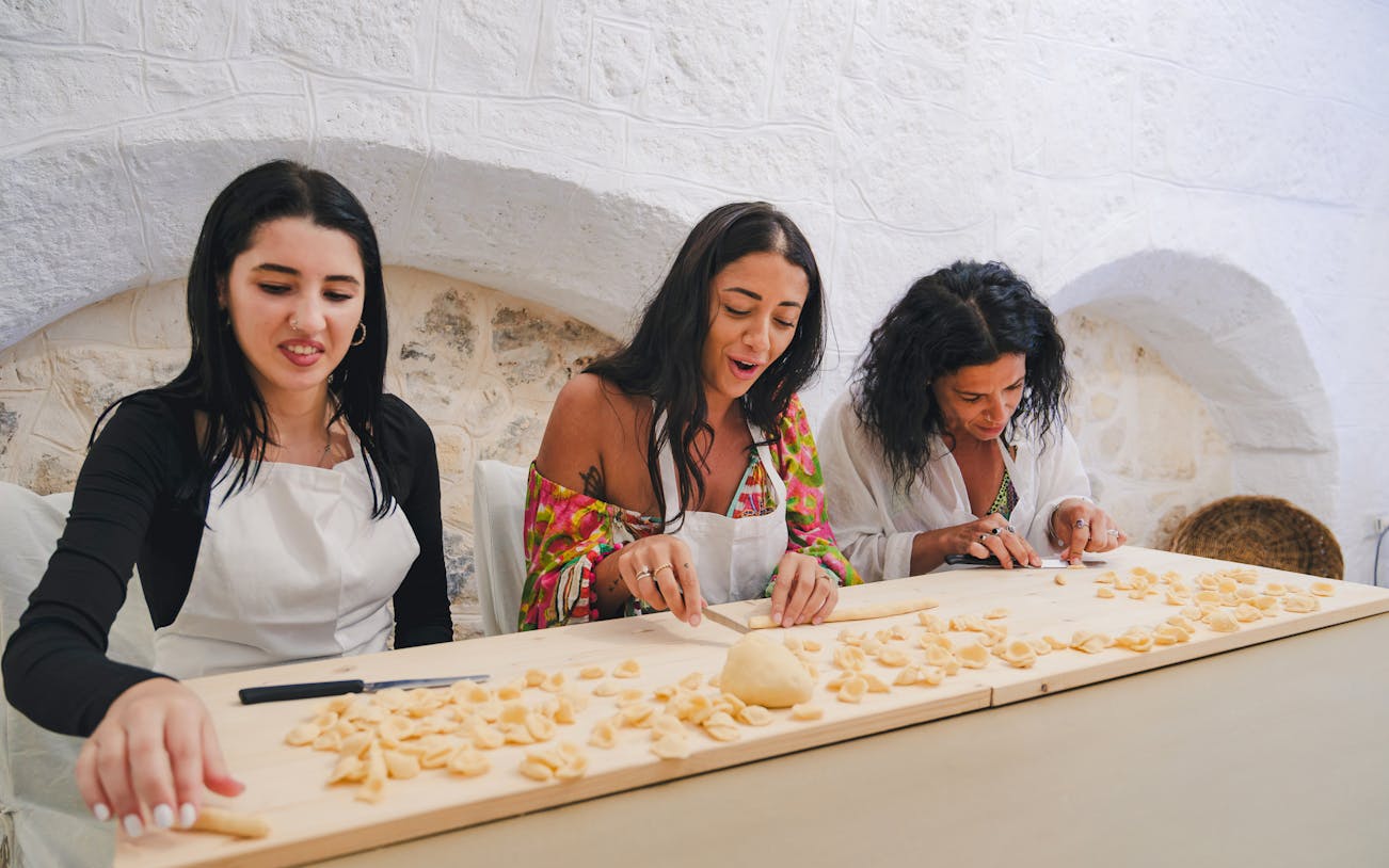 Women making pasta at Polignano a Mare cooking class in Italy.