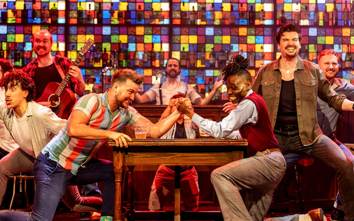 Men arm wrestling on stage during The Choir of Man performance.