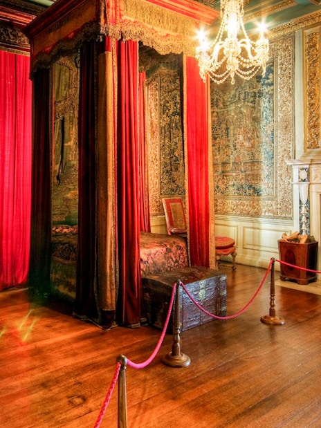 Warwick Castle bedroom with ornate canopy bed, tapestries, and fireplace.