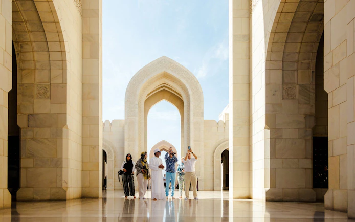 Guide with tourists at Royal Opera House entrance, Muscat.