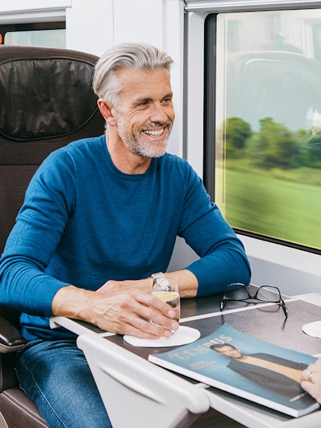 Travelers enjoying drinks in first-class seats on a Eurail train.