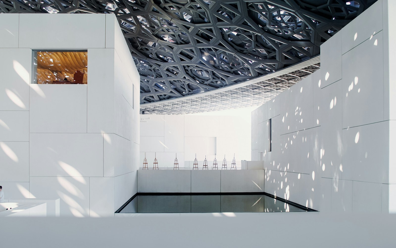 Louvre Abu Dhabi interior with geometric ceiling and light patterns.
