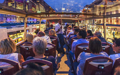 Evening city tour on an open-top bus in Vienna with passengers enjoying the view.