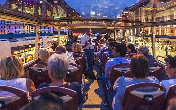 Evening city tour on an open-top bus in Vienna with passengers enjoying the view.