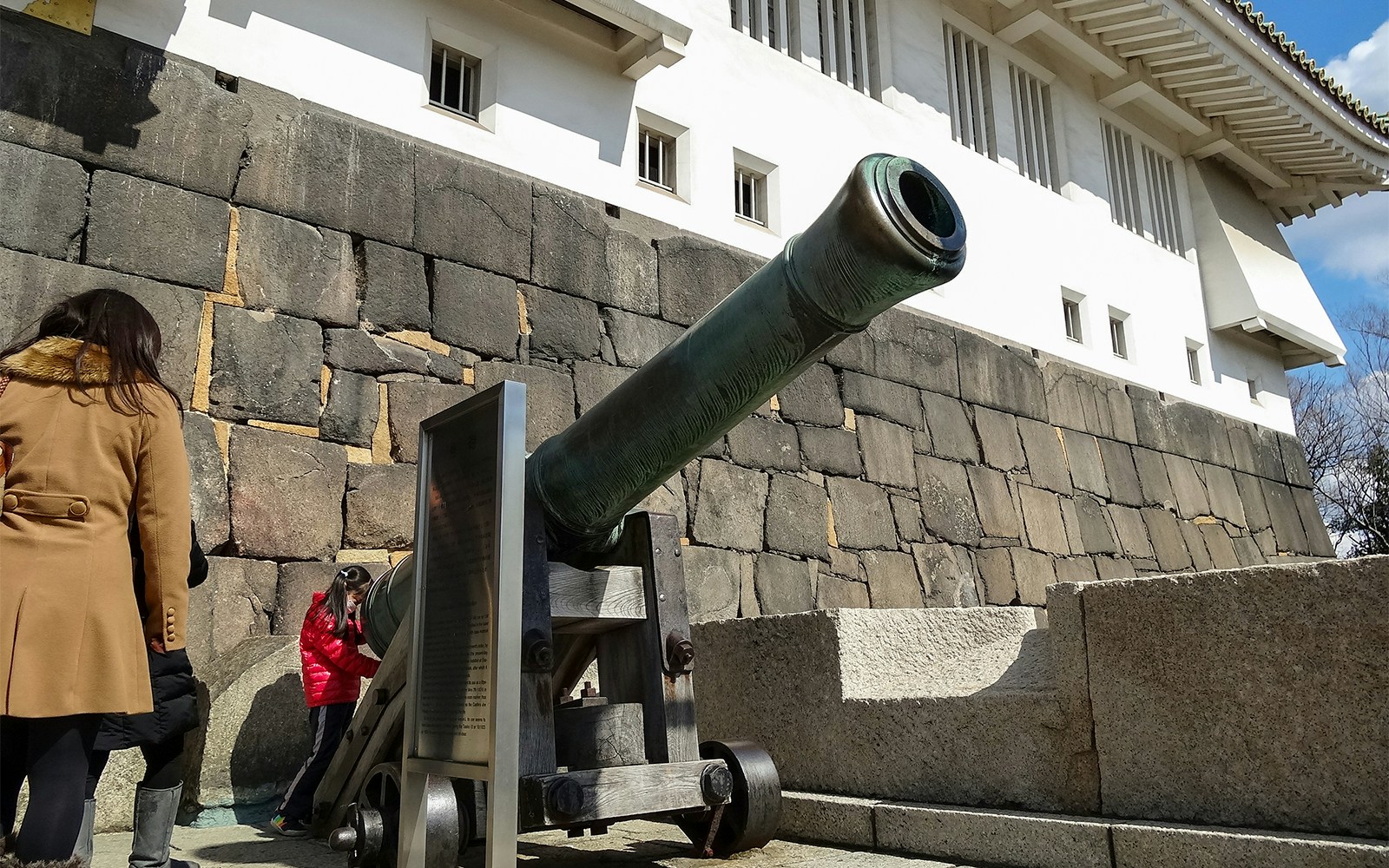 Cannon at Osaka Castle with visitors exploring the historic stone walls.